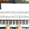 Foto 2 Mikrokosmos 2 Hände spielen Klavier; Notenblätter und Tastennummerierung oben sichtbar.