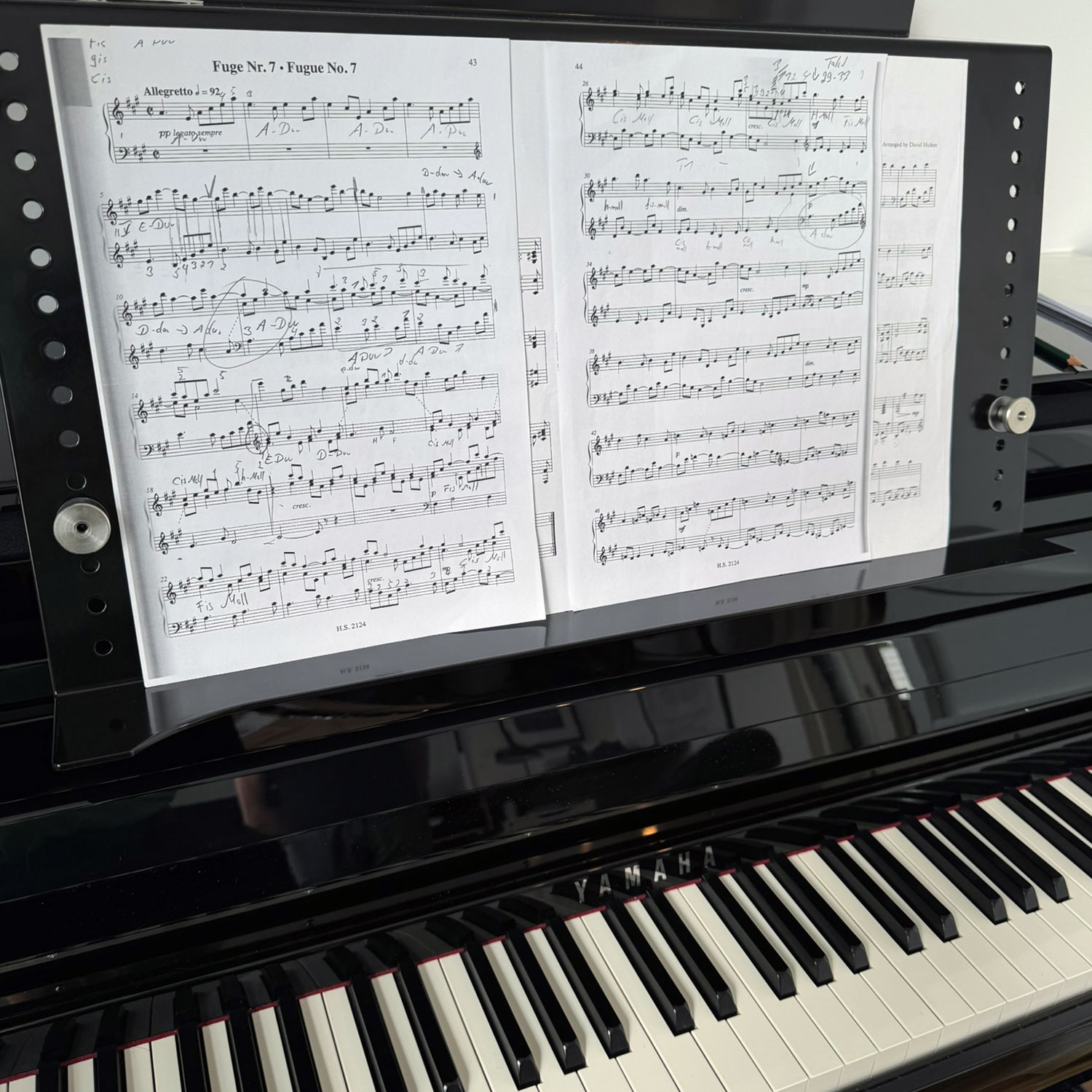 Notenblätter auf einem Notenständer, der auf einem Yamaha-Klavier steht, sichtbar sind mehrere Notenlinien und Schlüssel.